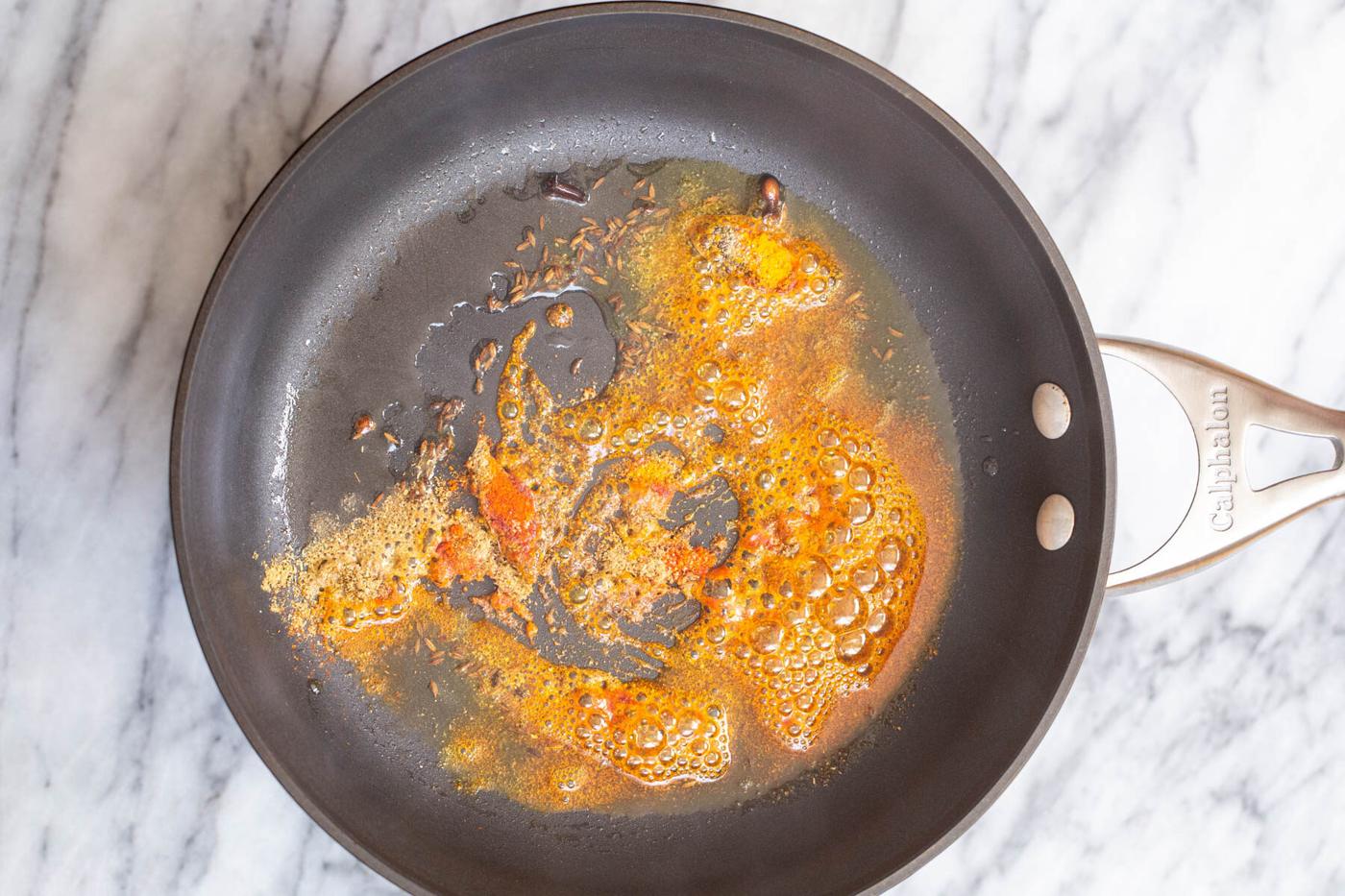 ground spices being added to tempering to make ural dal