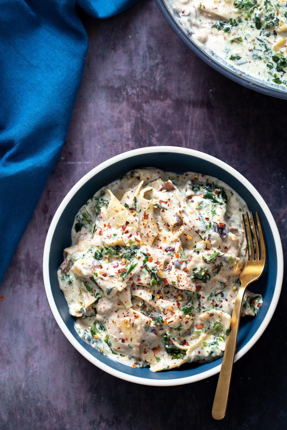 a blue bowl filled with vegan alfredo skillet lasagna