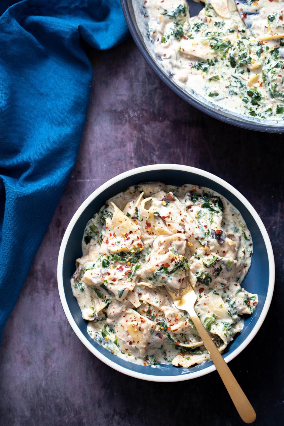 a serving of vegan mushroom spinach skillet lasagna served in a bowl with a golden fork