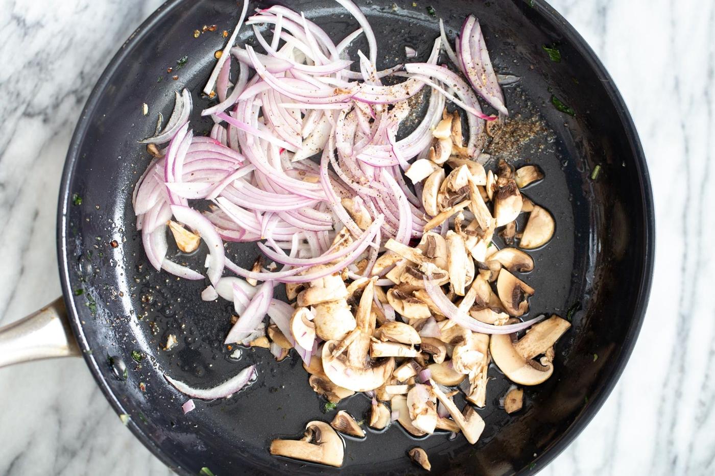 onions and mushrooms being added to a frying pan