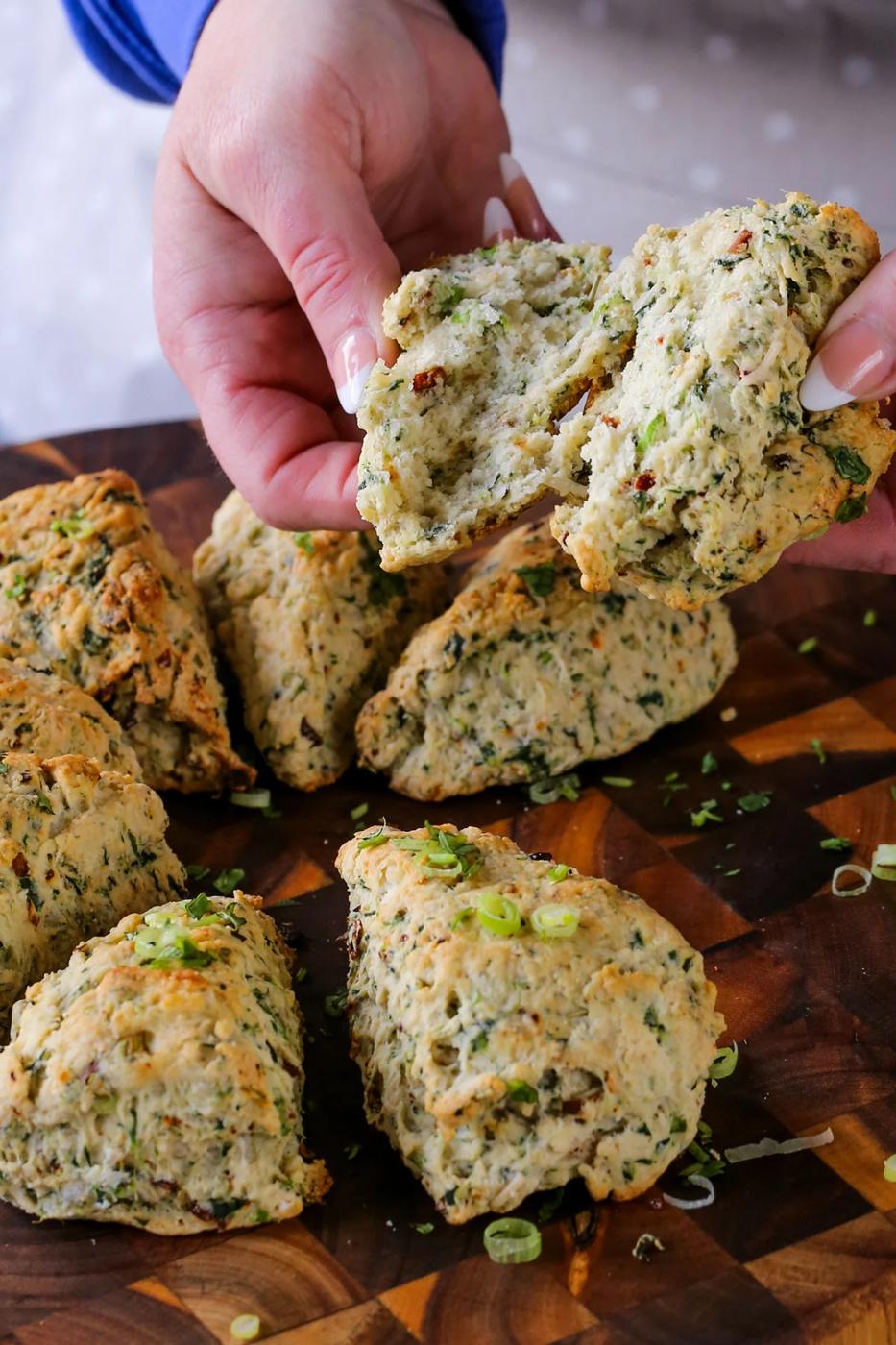 holding a vegan savory scone torn in half, so you can see the texture inside
