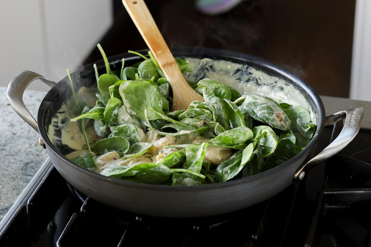 adding spinach to the pan