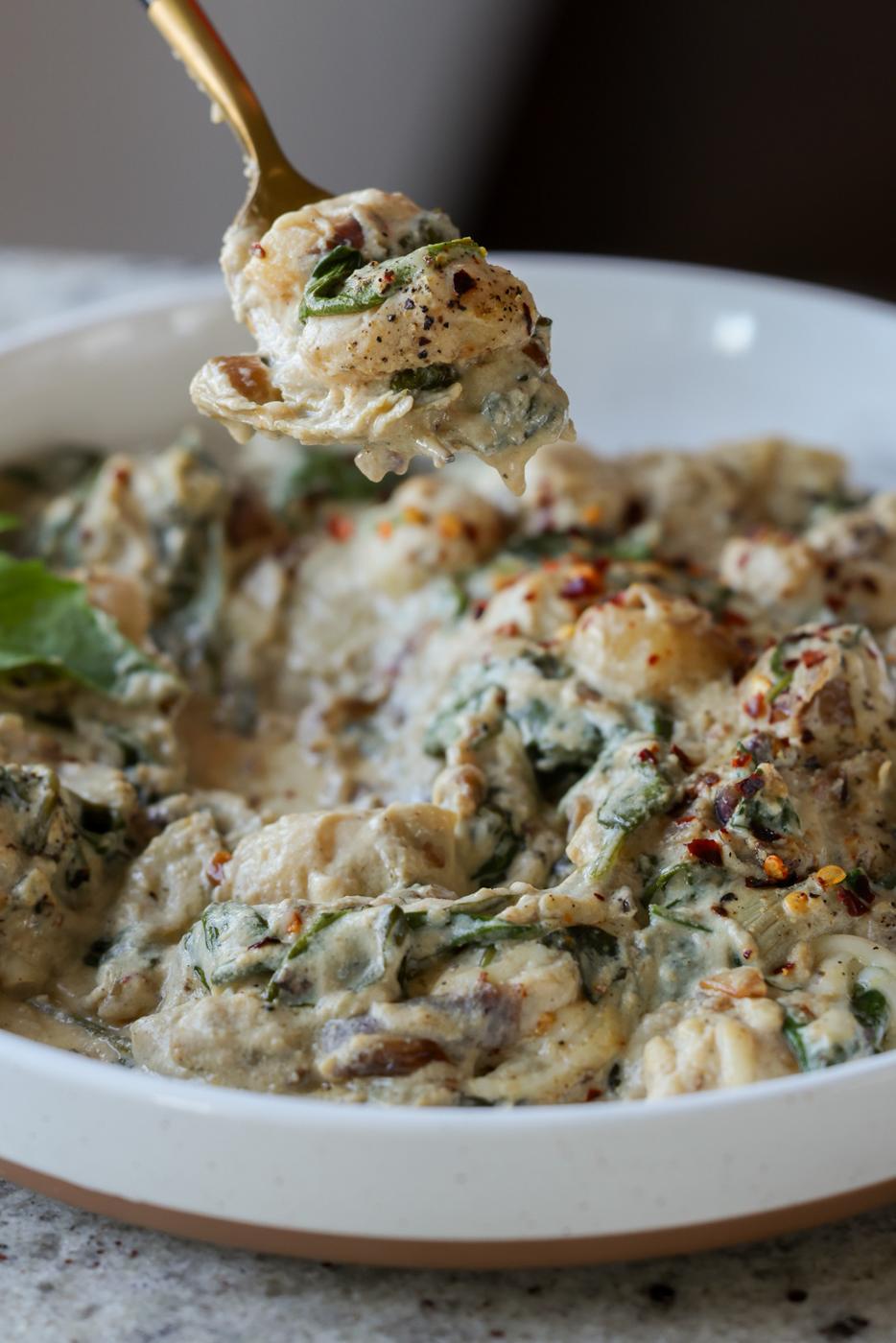 fork taking a bite of spinach artichoke gnocchi