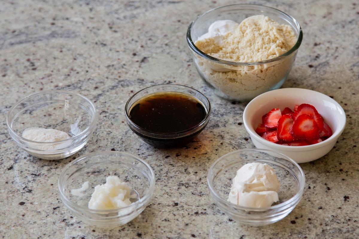 almond flour, strawberries, and other cookie ingredients in bowls on a kitchen counter