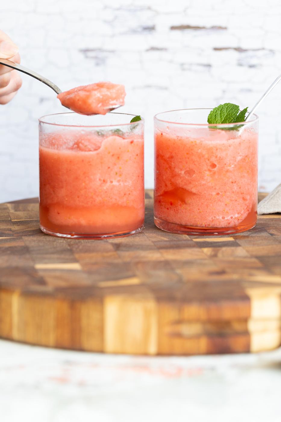 two glasses with homemade vegan strawberry lemonade slushies on a wooden board