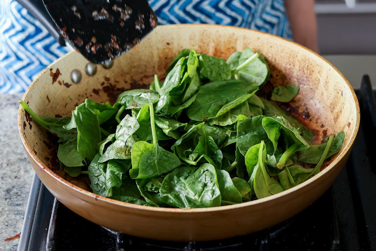 adding spinach to the pan