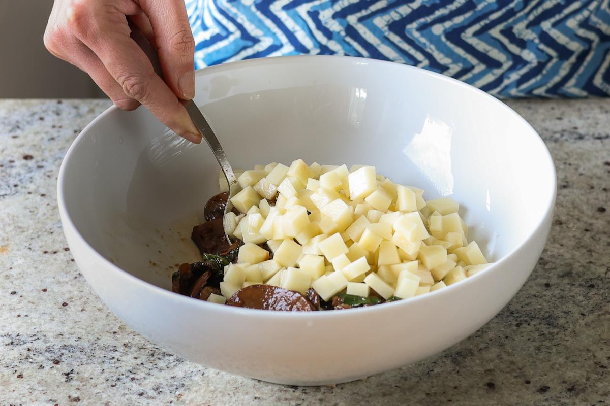 adding potatoes to the mushroom and spinach mixture