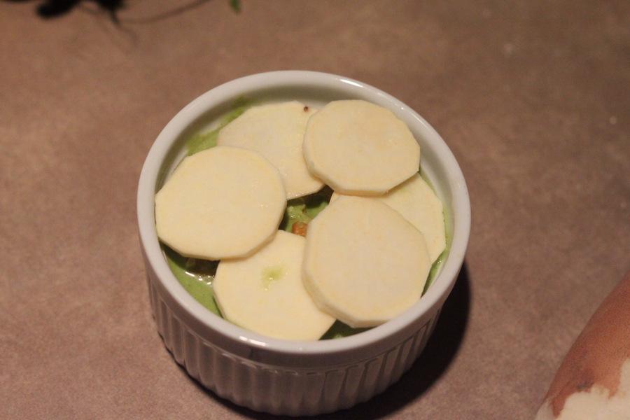 white sweet potatoes, spinach alfredo sauce and bell pepper being layered in a casserole dish to make alfredo bake