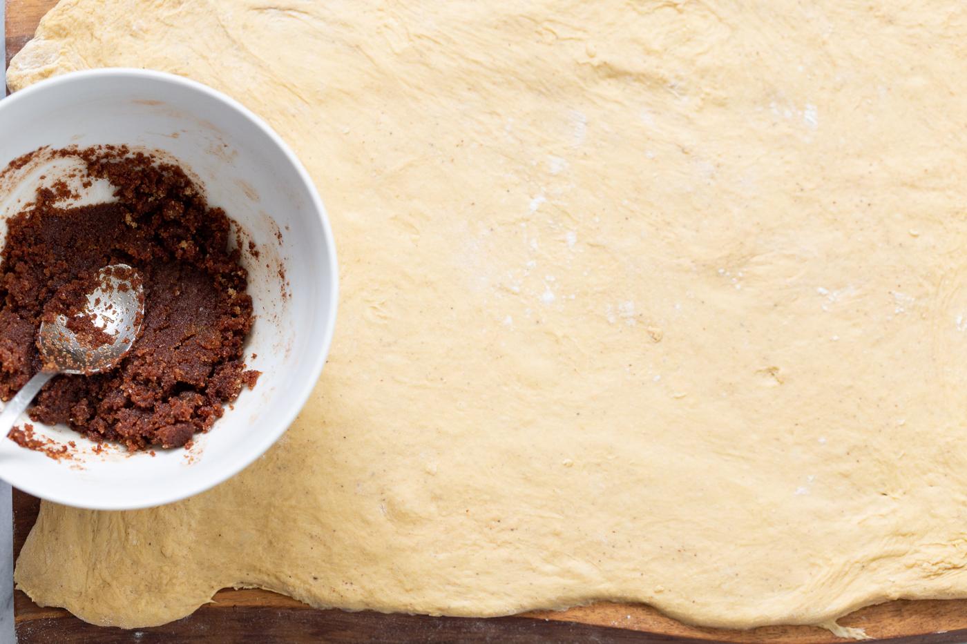 brown sugar cinnamon mixture being spread on top of no yeast cinnamon roll dough