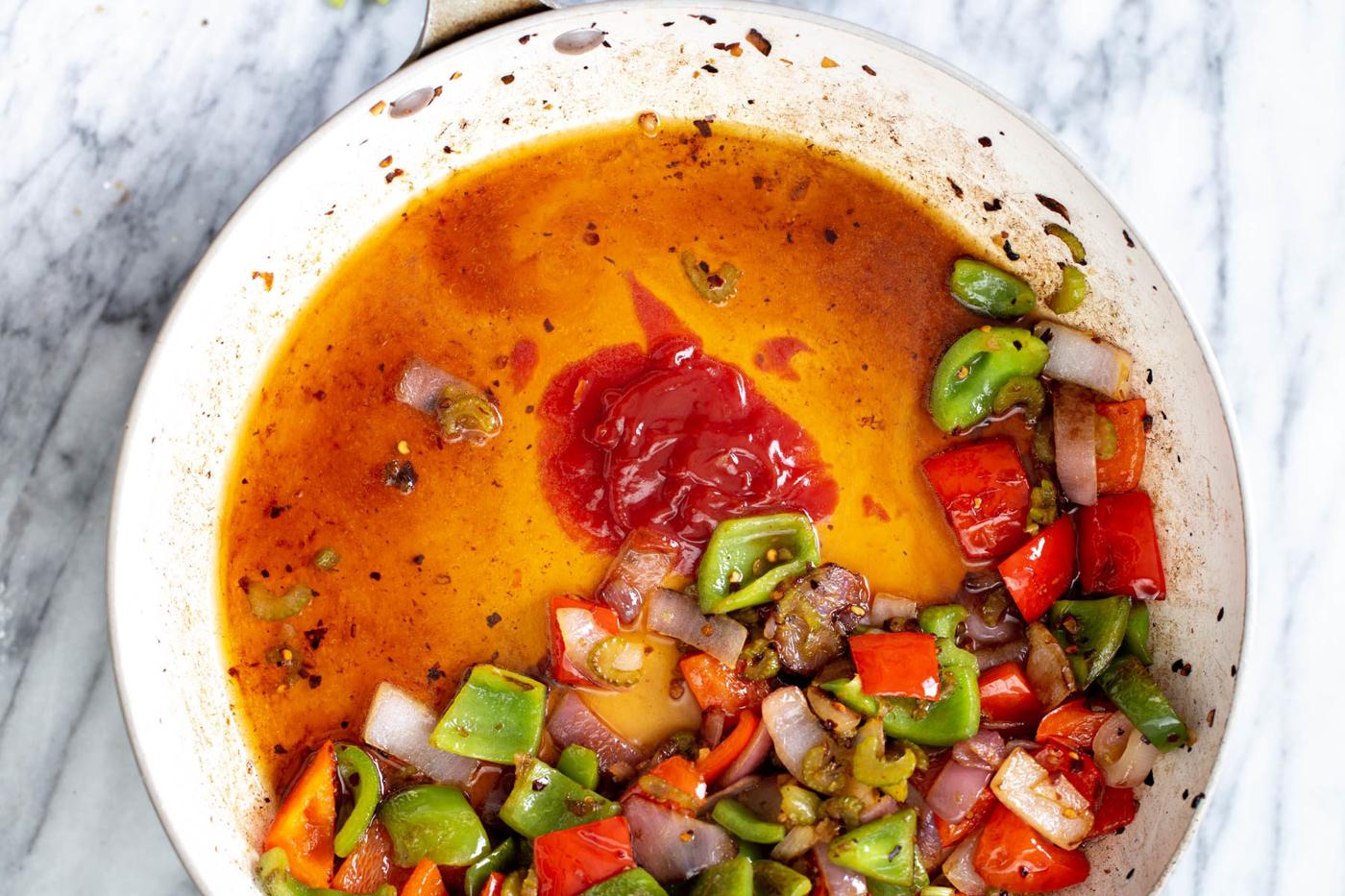 stir-fry sauce being added to a frying pan with vegetables to make sweet and sour tofy