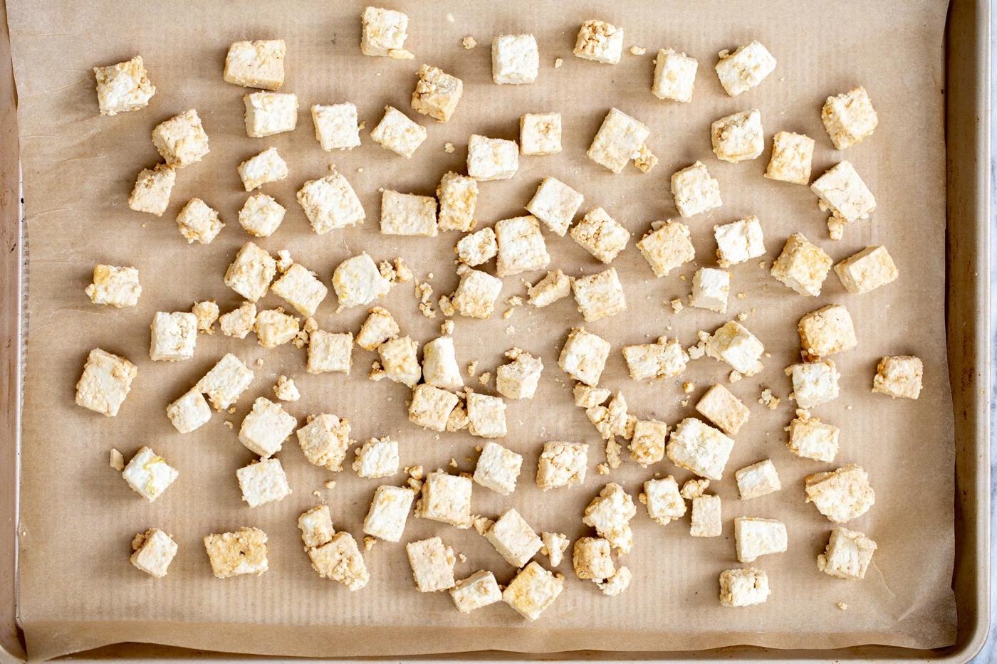 overhead shot of tofu cubes coated in cornstarch on a baking sheet