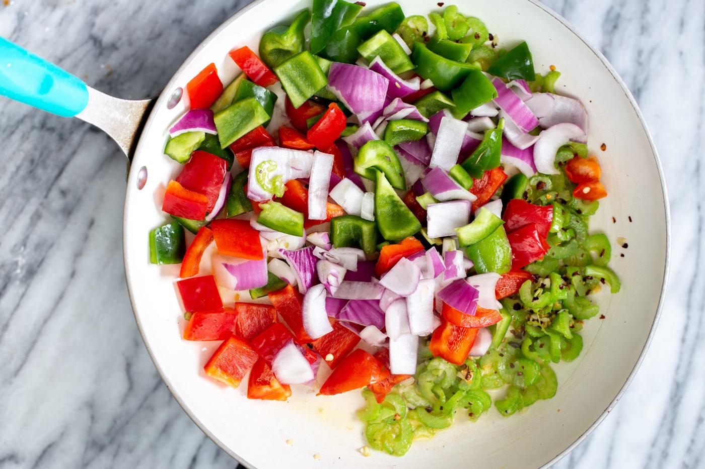 chopped onion and bell pepper in a frying pan