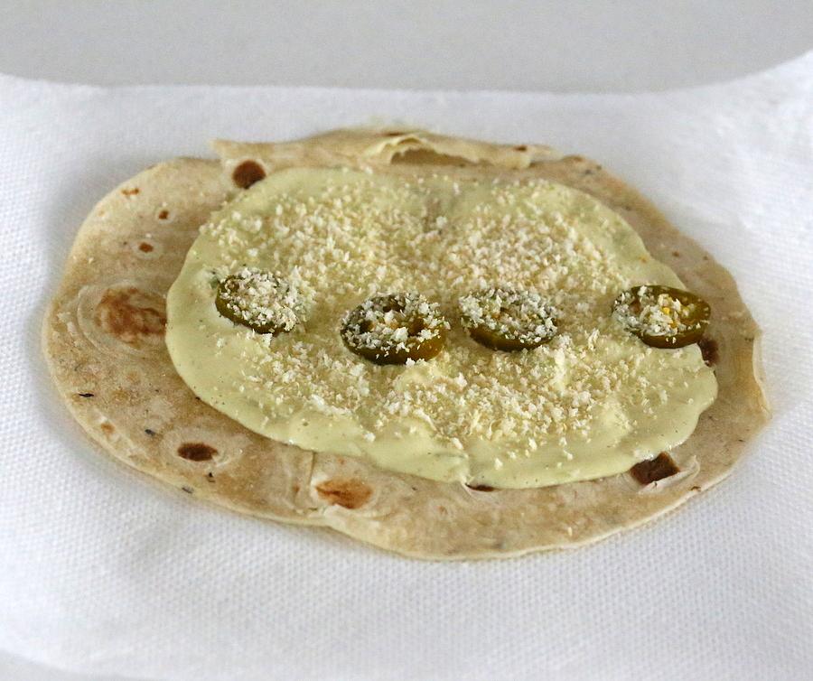 cashew jalapeno popper dip being spread on a wheat tortilla to make vegan breakfast wrap