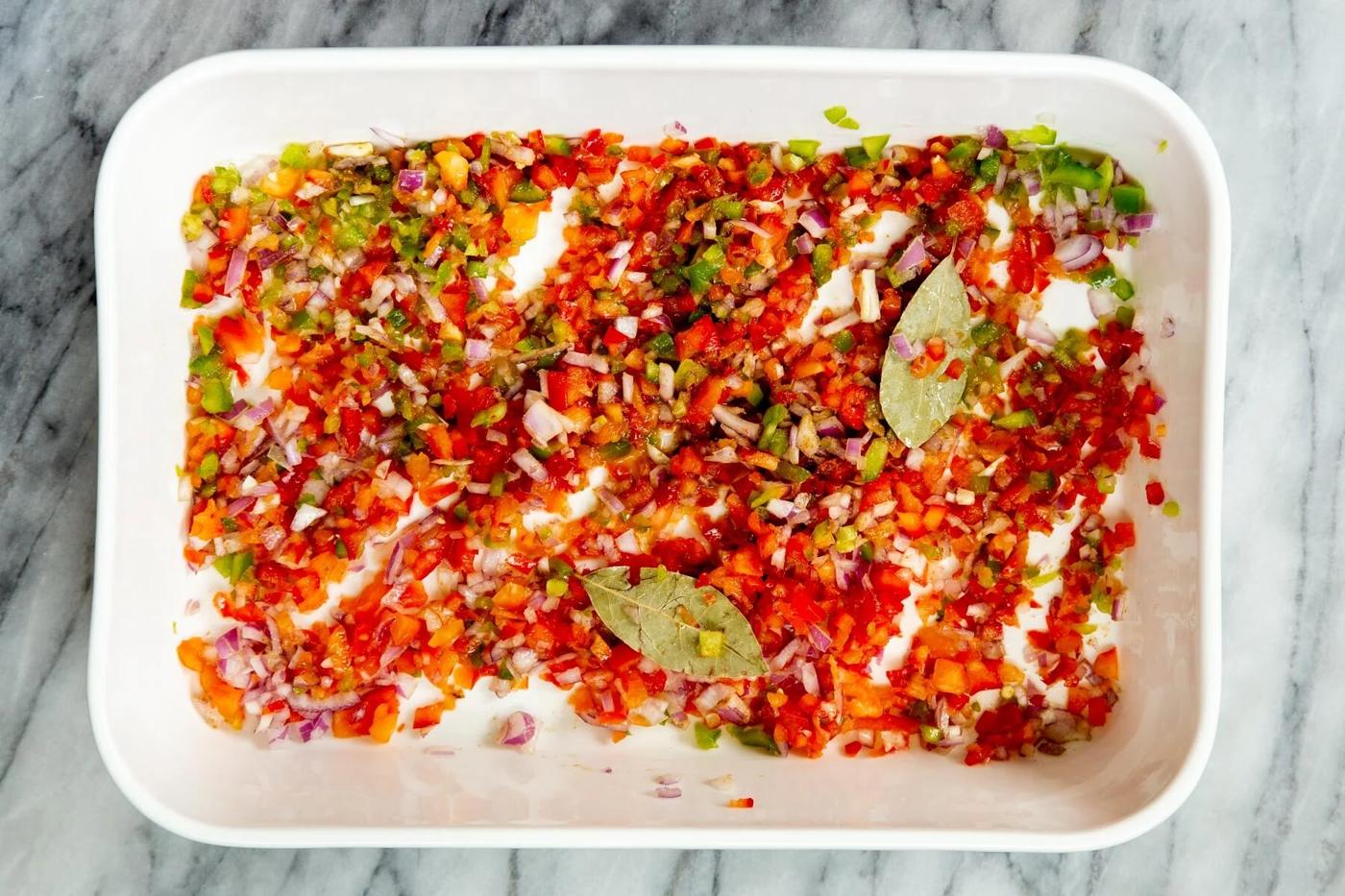 sauteed chopped onion and bell pepper in a white casserole dish
