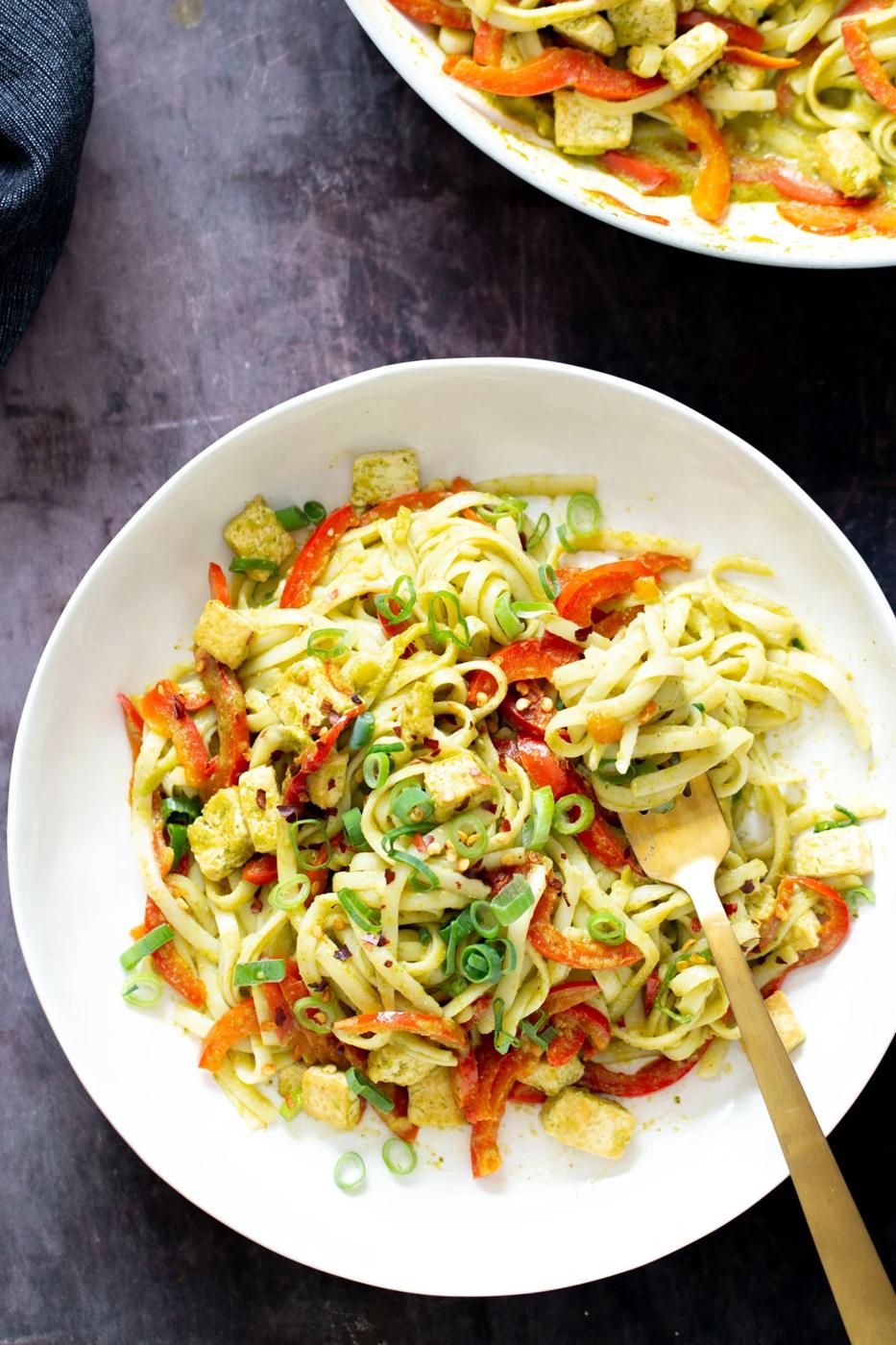a fork twirling vegan Thai Green Curry Noodles in a noodle bowl