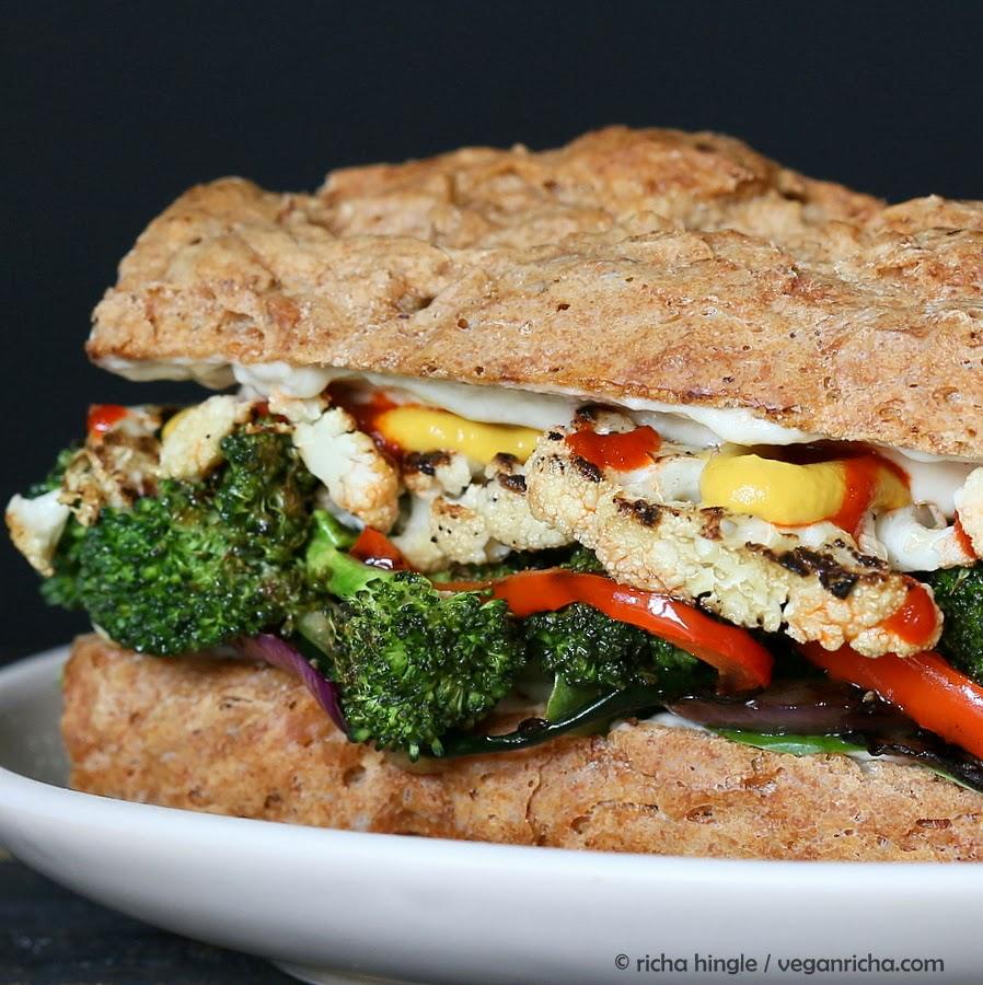 close-up side view of a roasted vegetable sandwich with sriracha mayo on a spelt almond flour bun