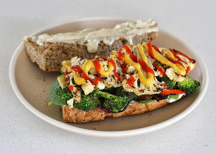 open-faced vegan grilled vegetable sandwich with plenty of sriracha mayo and mustard drizzled on top