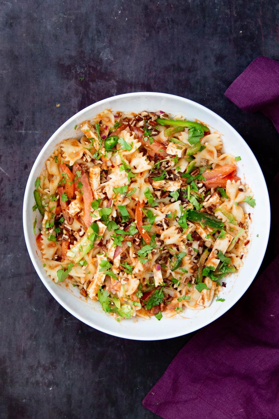 vegan tikka masala pasta salad in white bowl, sprinkled with chopped herbs