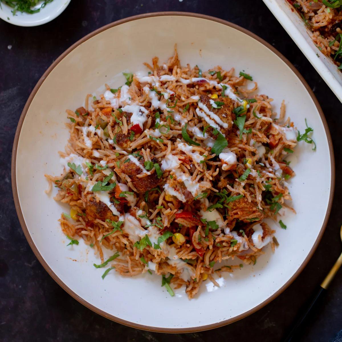 plate of tikka masala rice topped with yogurt and cilantro