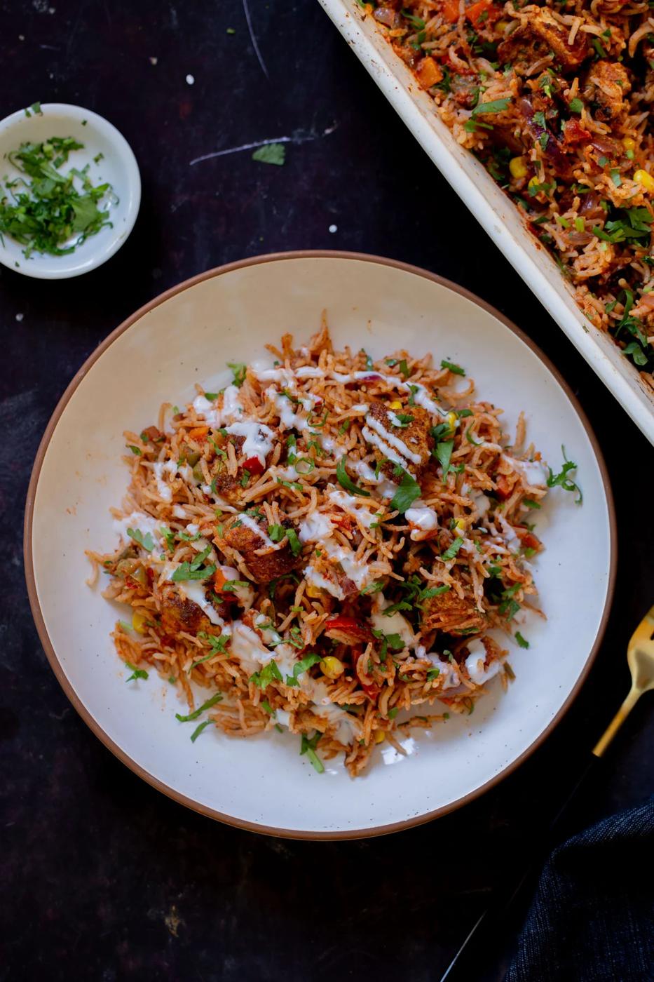 plate of tikka masala rice topped with yogurt and cilantro