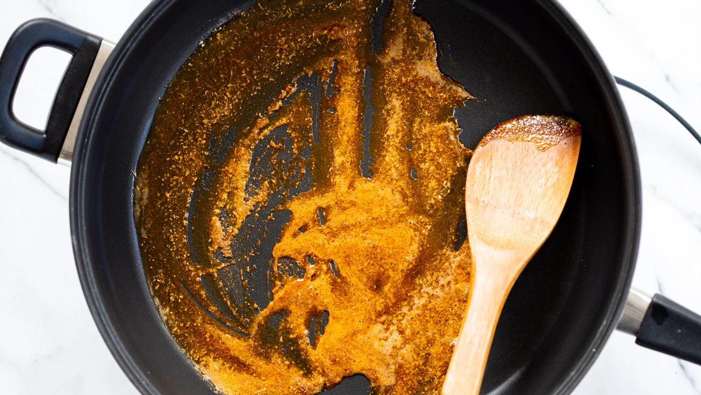 Our Vegan Tofu Amritsari Masala Sauce step with spices getting toasted in a black skillet