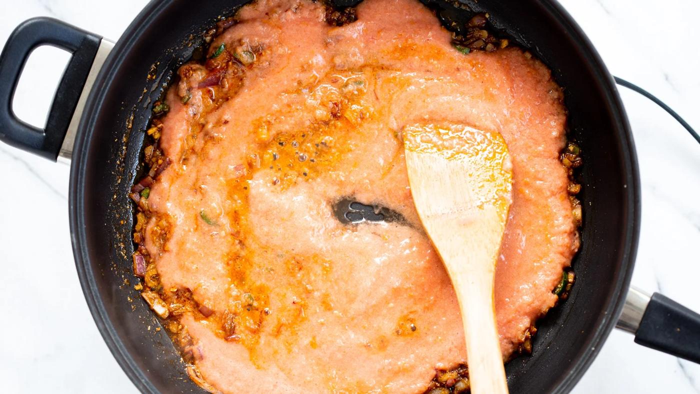 TomatoCashew sauce getting cooked with spices in a black skillet for Our Vegan Tofu Amritsari Masala Sauce