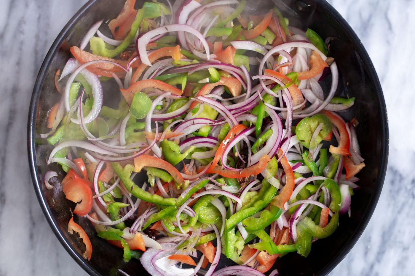 sauteed bell peppers and onions in a skillet