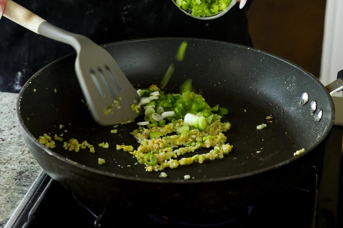 adding green onion to the pan