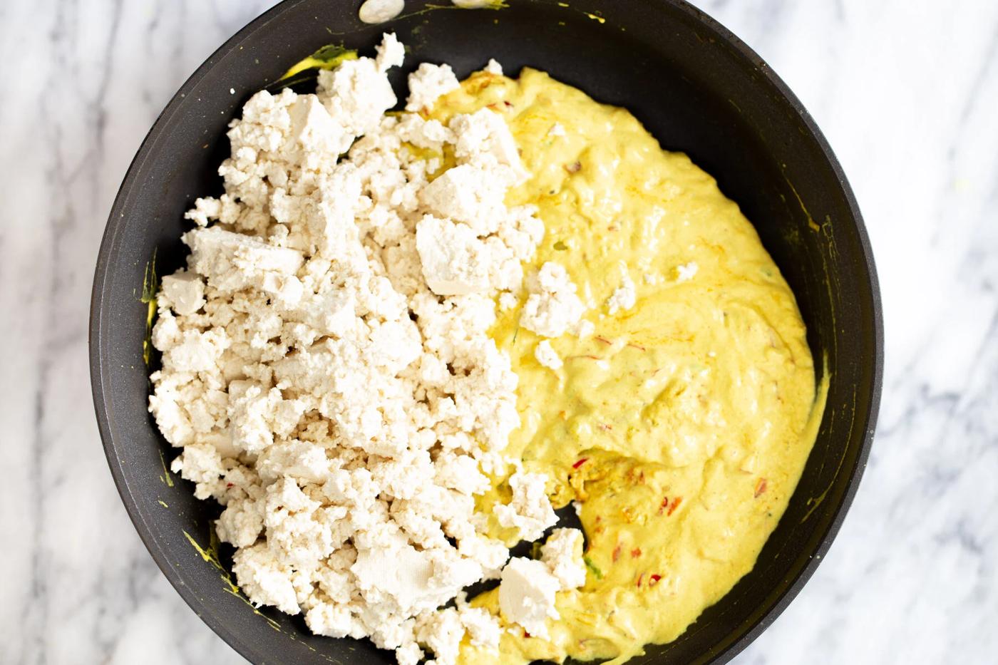crumbled tofu being added to a pan to make tofu scramble