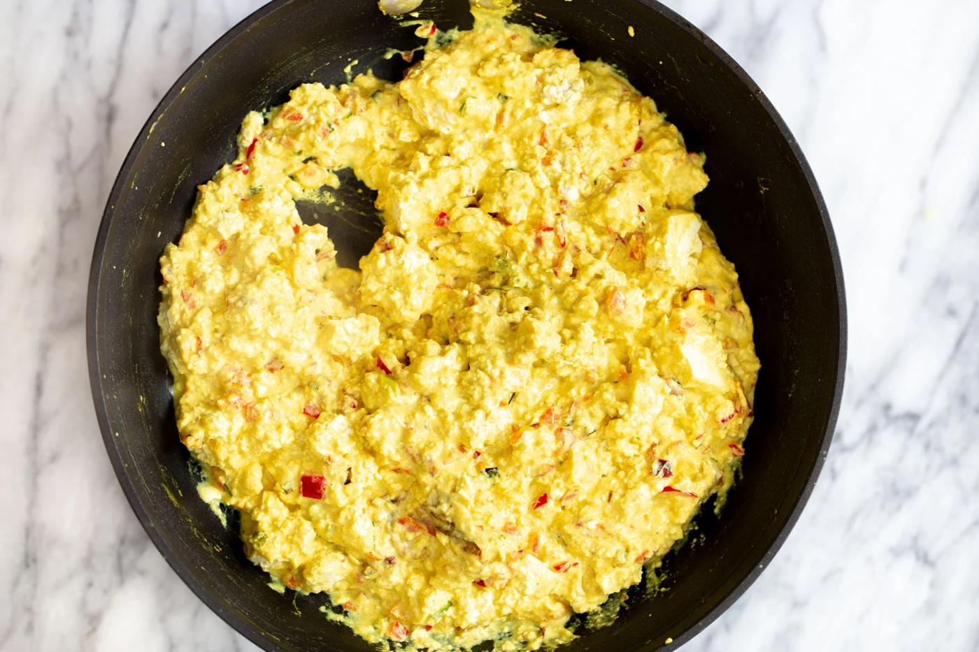vegan tofu scramble being prepared in a black skillet