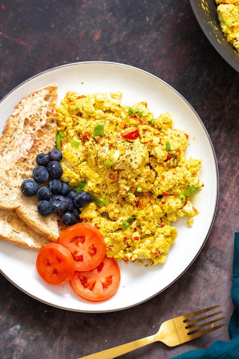 vegan scrambled eggs made with tofu scramble seasoning served with blueberries, toast and tomatoes