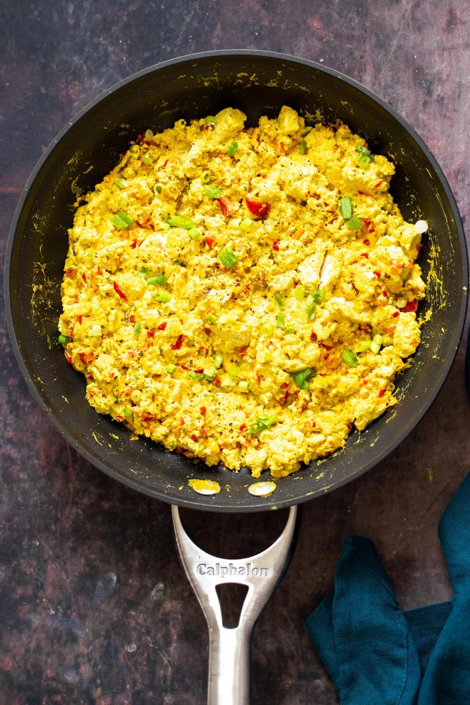a black skillet with vegan tofu scramble with bell peppers and green onions