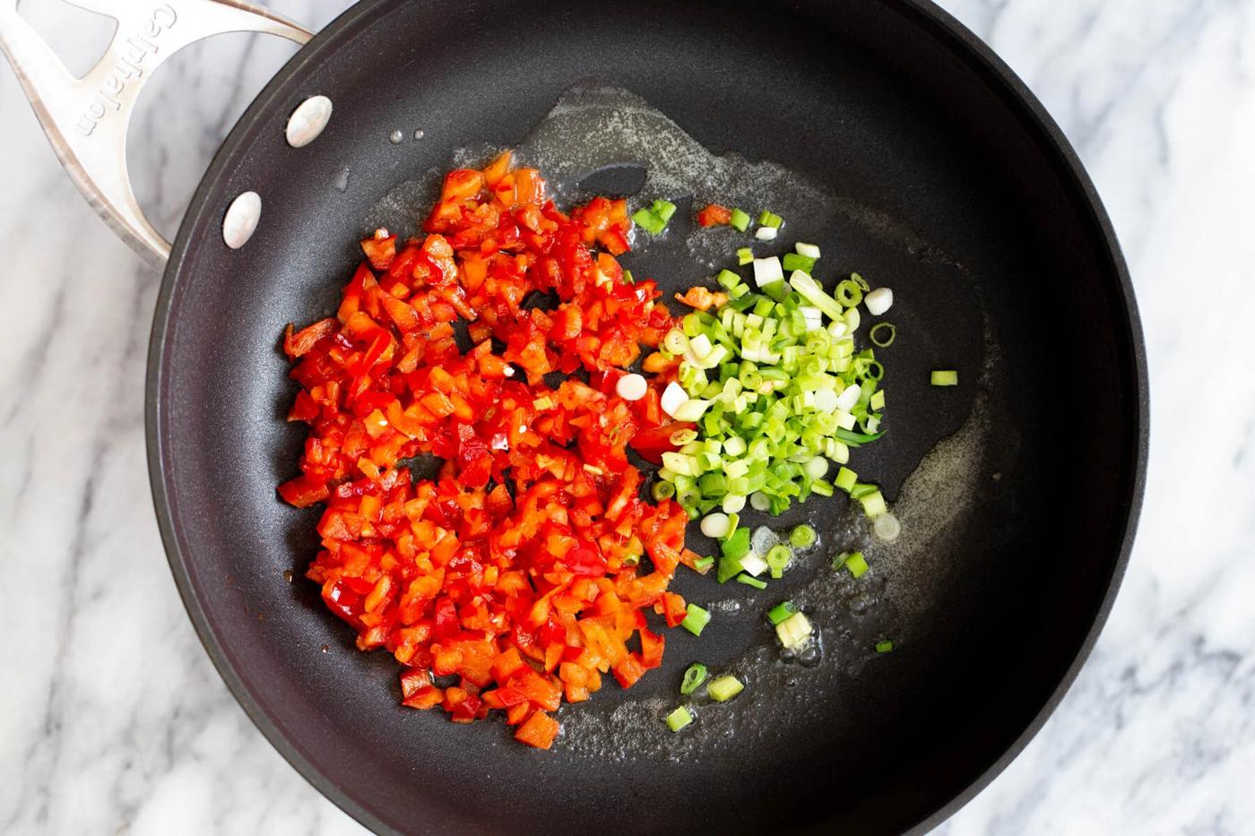 bell pepper and green onions in a sauteeing pan