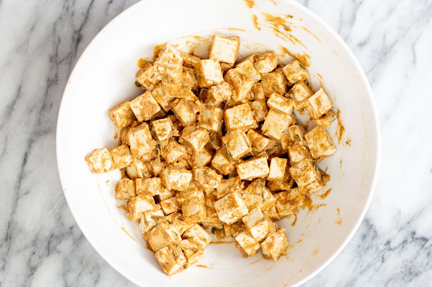 tofu cubes being tossed in tikka masala marinade