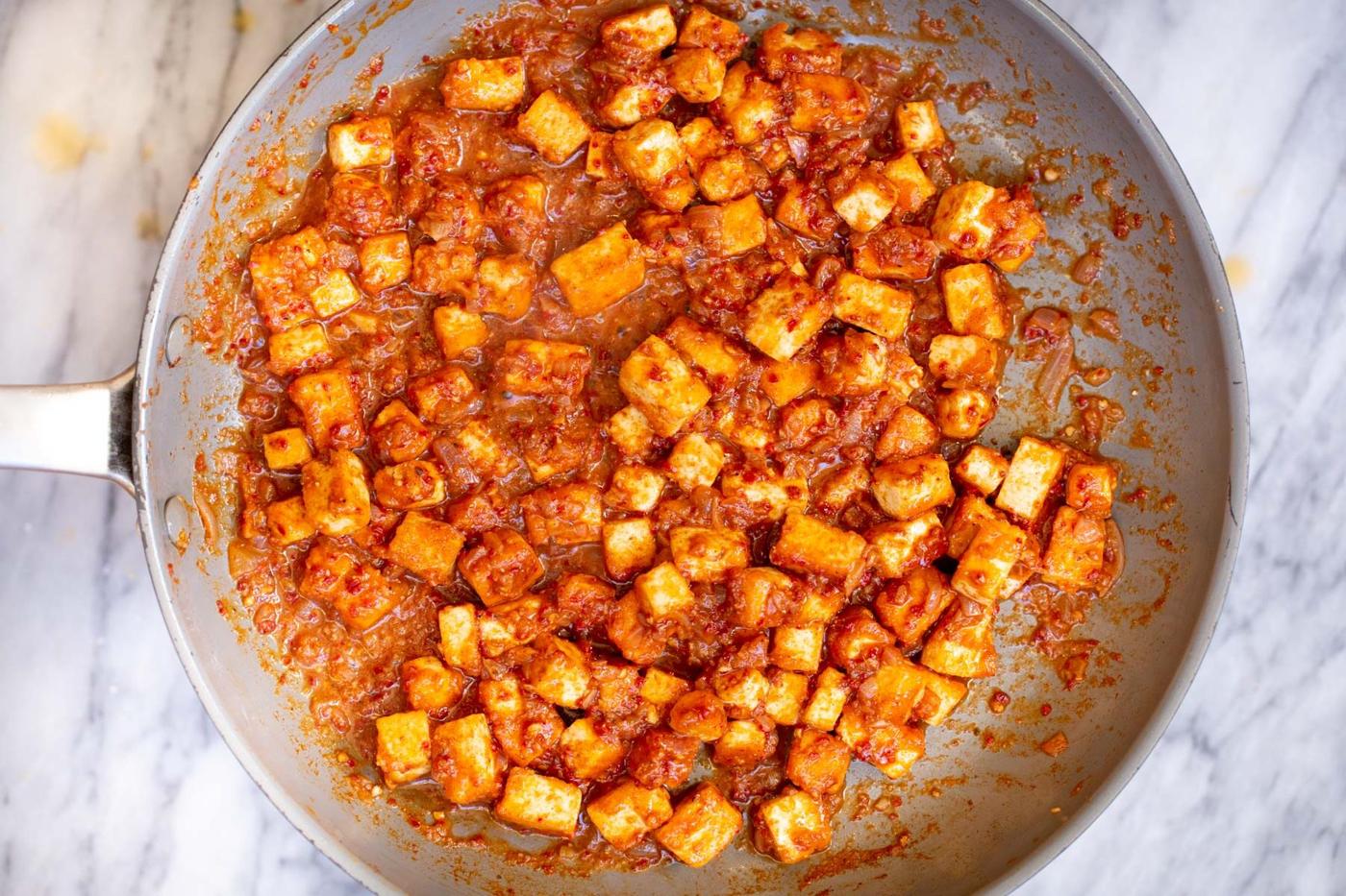 tofu cubes in a sauteeing pan on a marble countertop