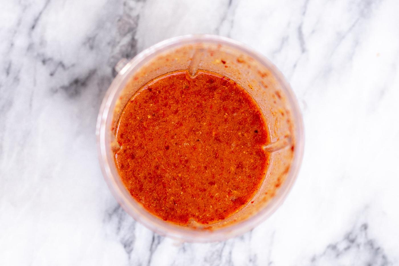 a small container with chili paste on a marble countertop