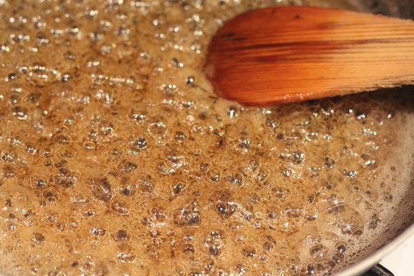 vegan coconut caramel sauce being stirred in a sauce pan with a wooden spoon