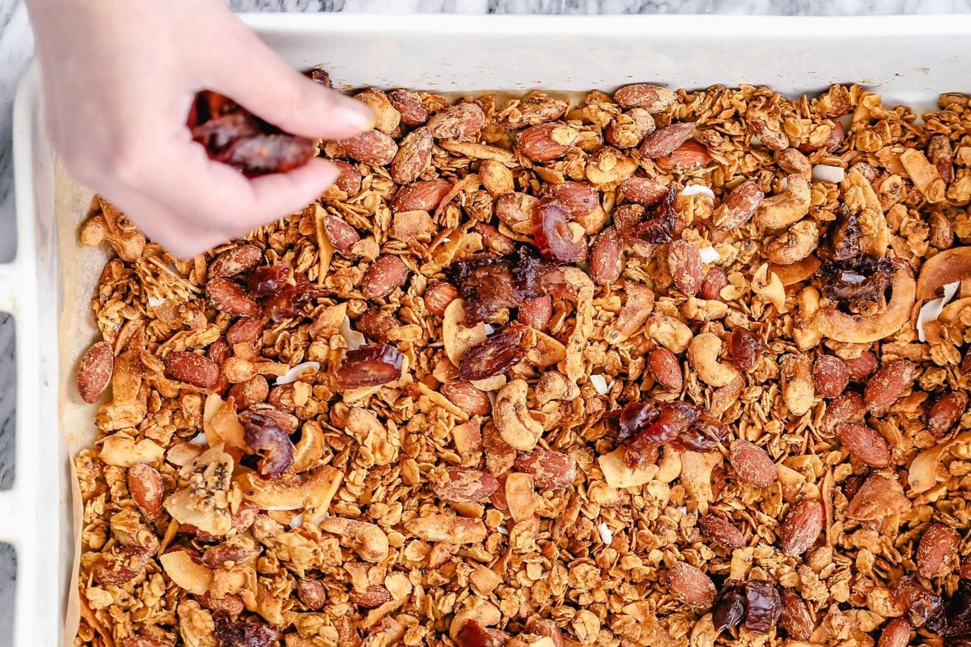 baked vegan granola being spread out in a casserole dish