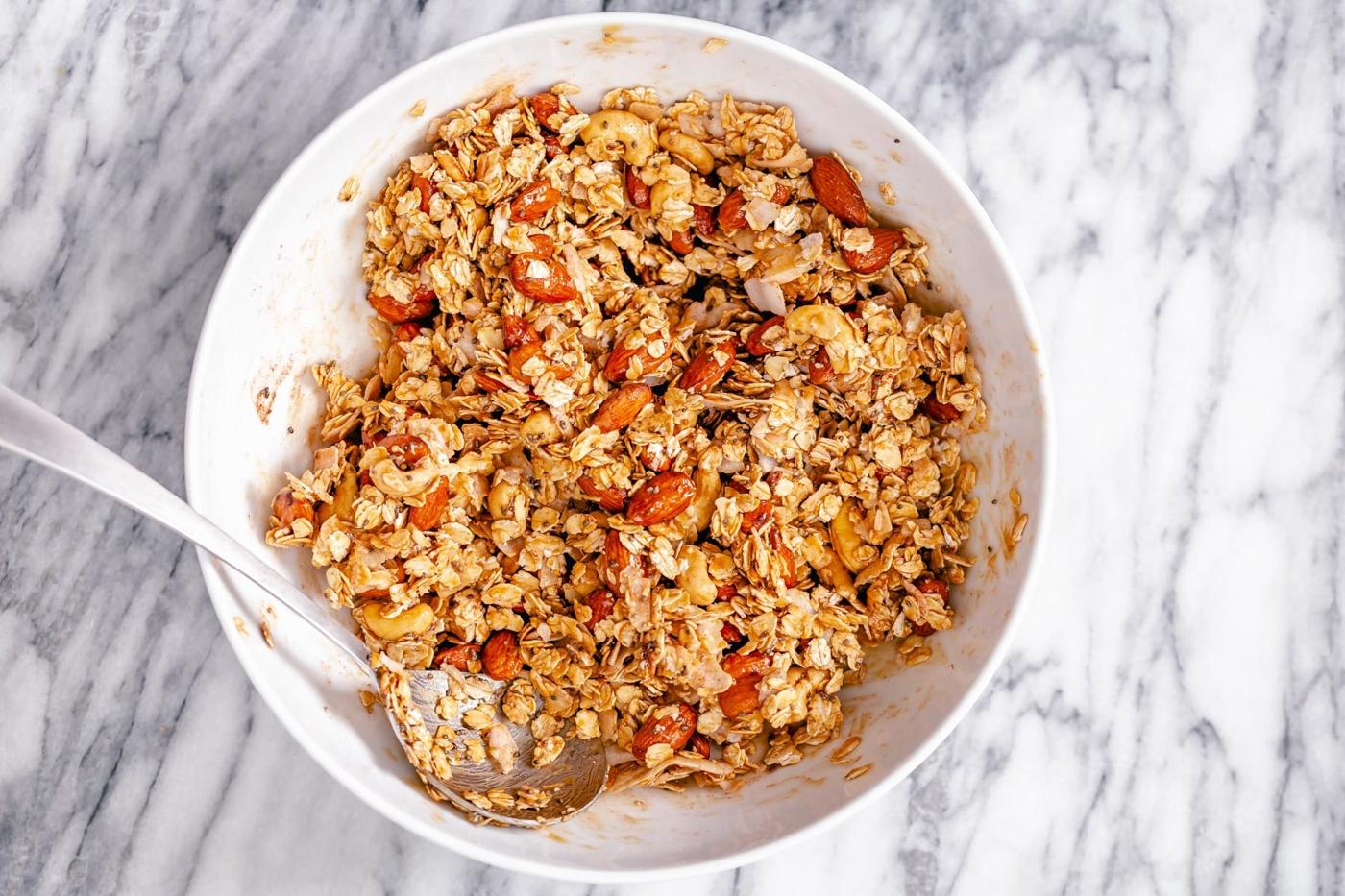almond coconut granola being mixed in a small white bowl