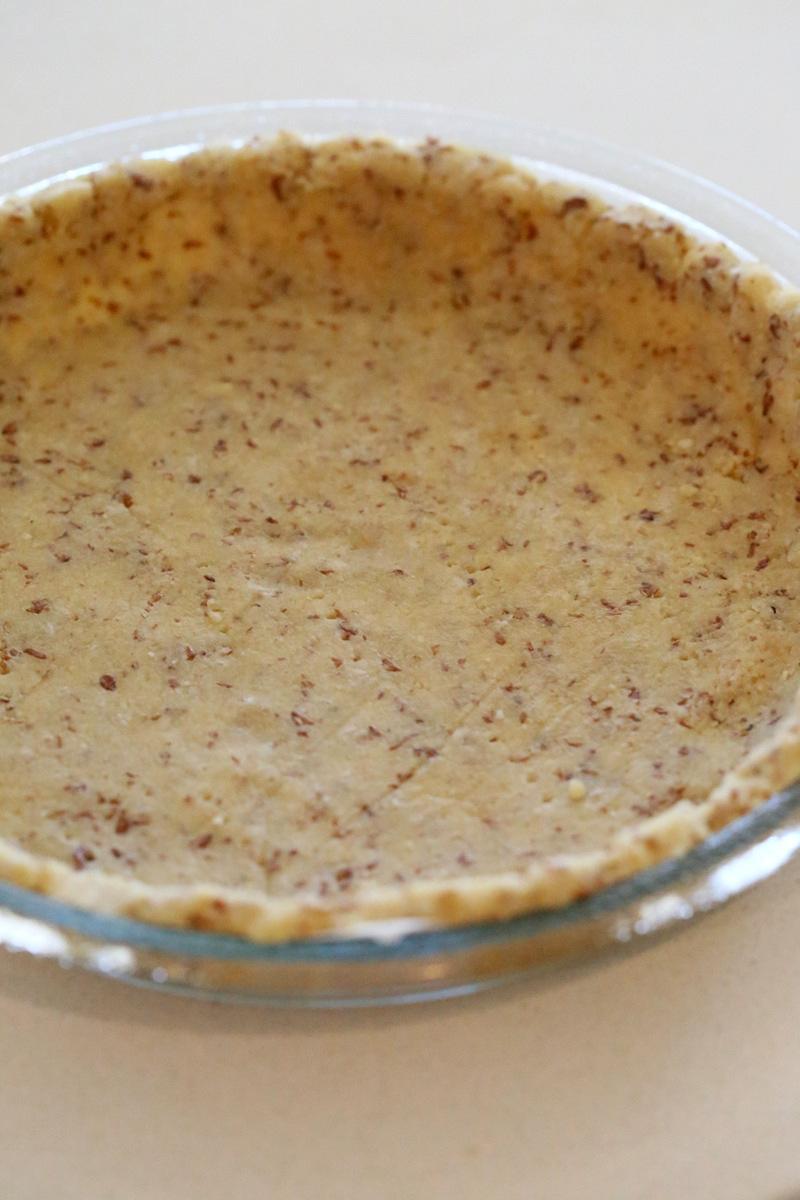 a healthy vegan almond flour pie crust in a Pyrex pie dish ready for baking