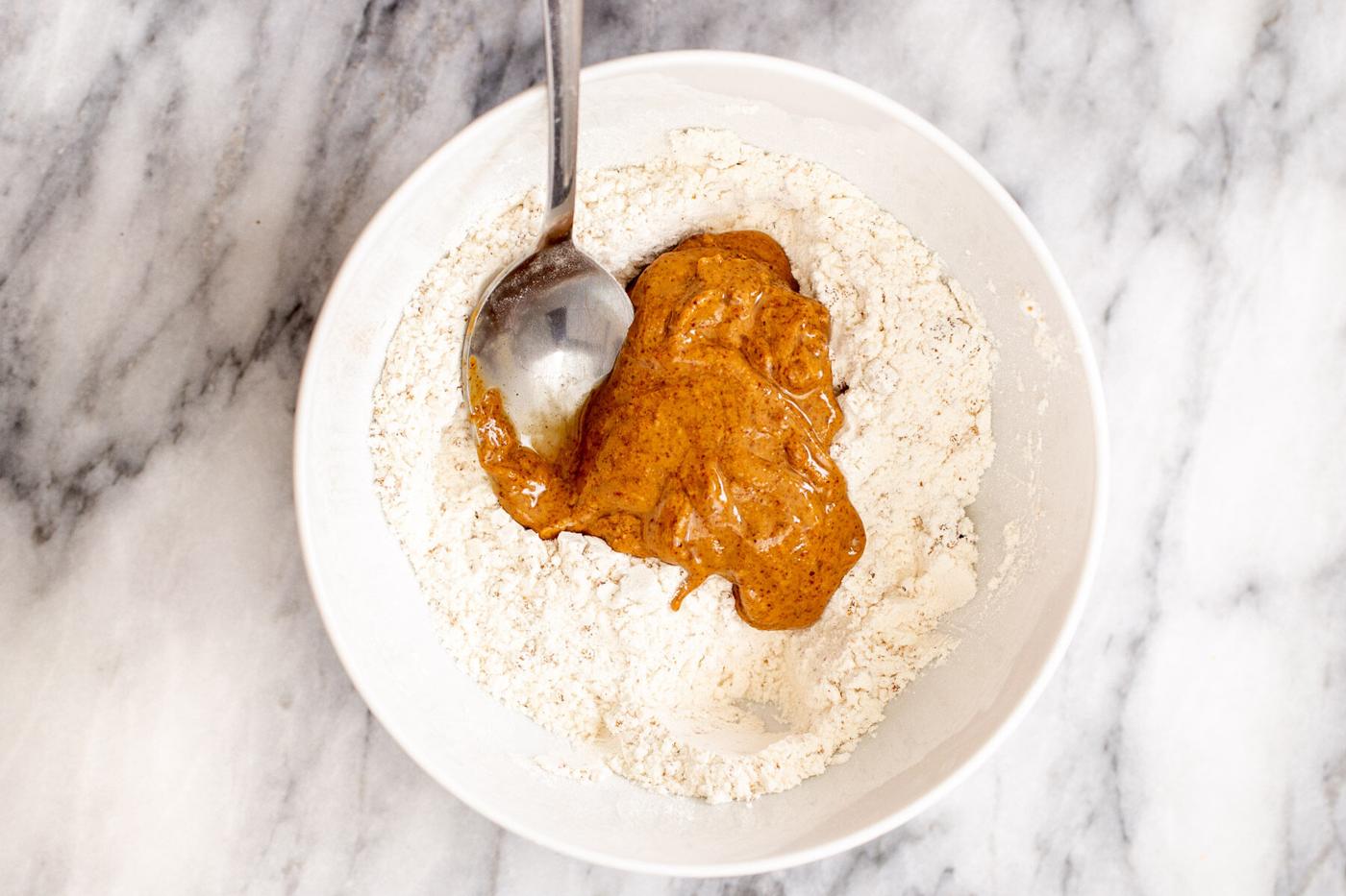 almond butter being mixed into dry crumble crust ingredients