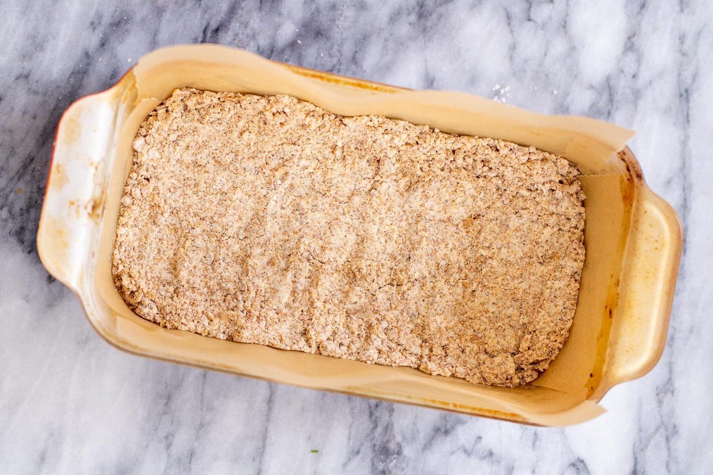 vegan apple pie crust being pressed in a baking dish