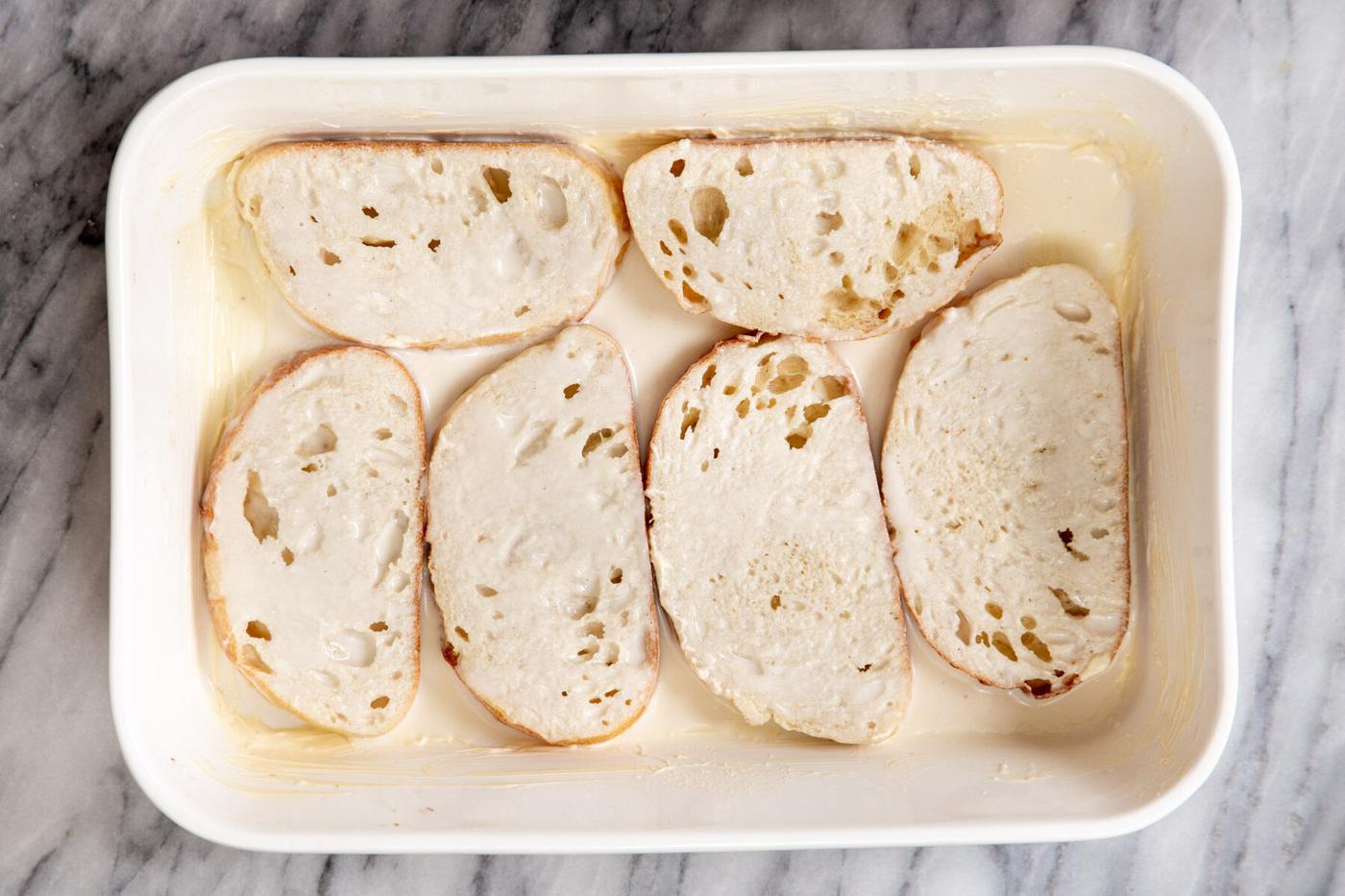 bread slices soaking in vegan cashew custard to make vegan baked french toast