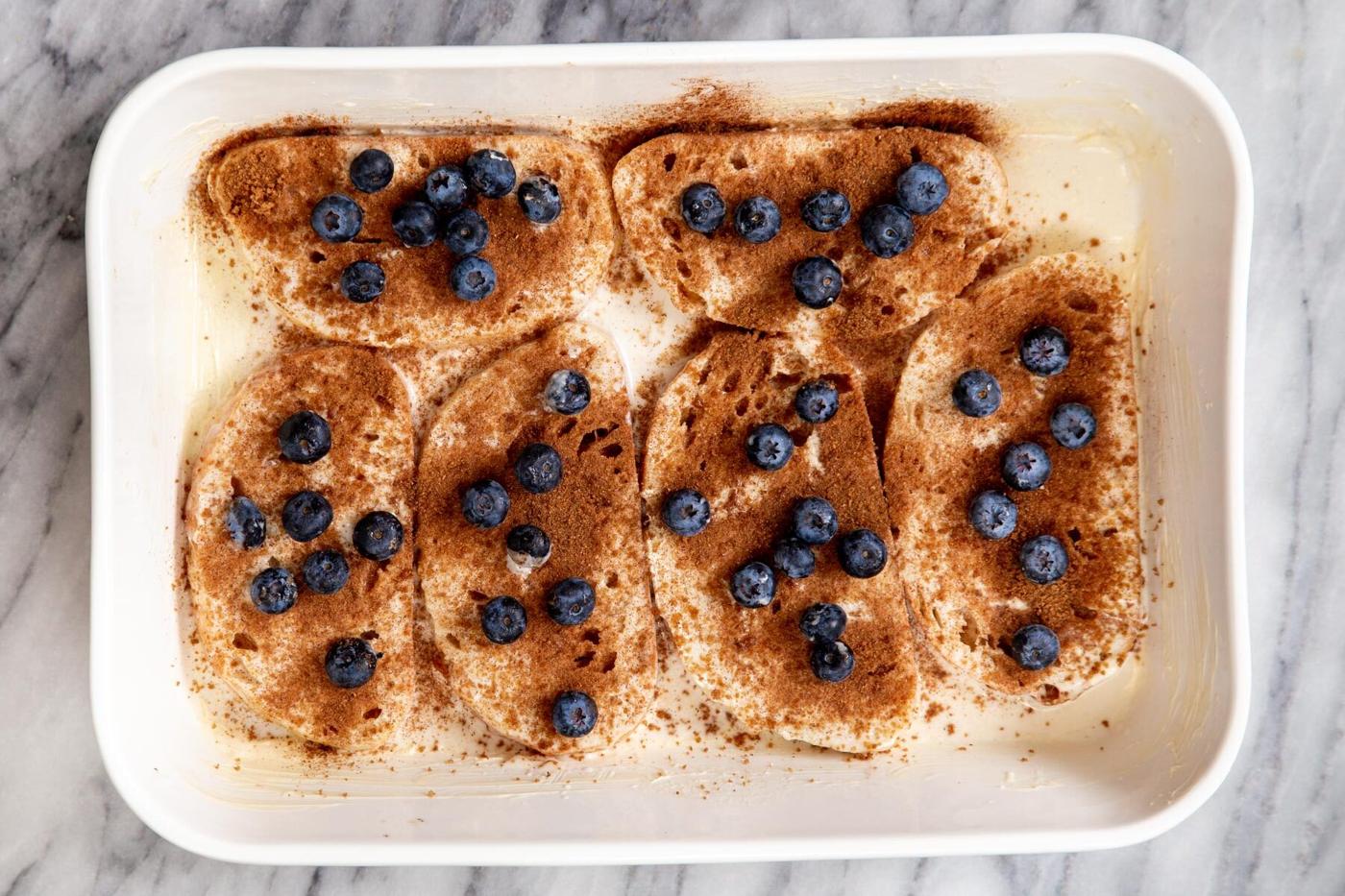 fresh blueberries being sprinkled over french toast casserole