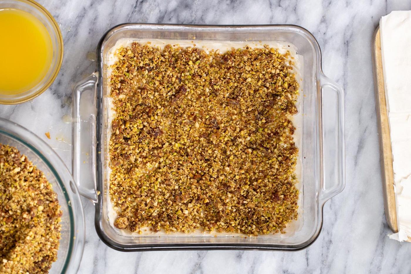 nuts and phyllo pastry being layered to make vegan baklava