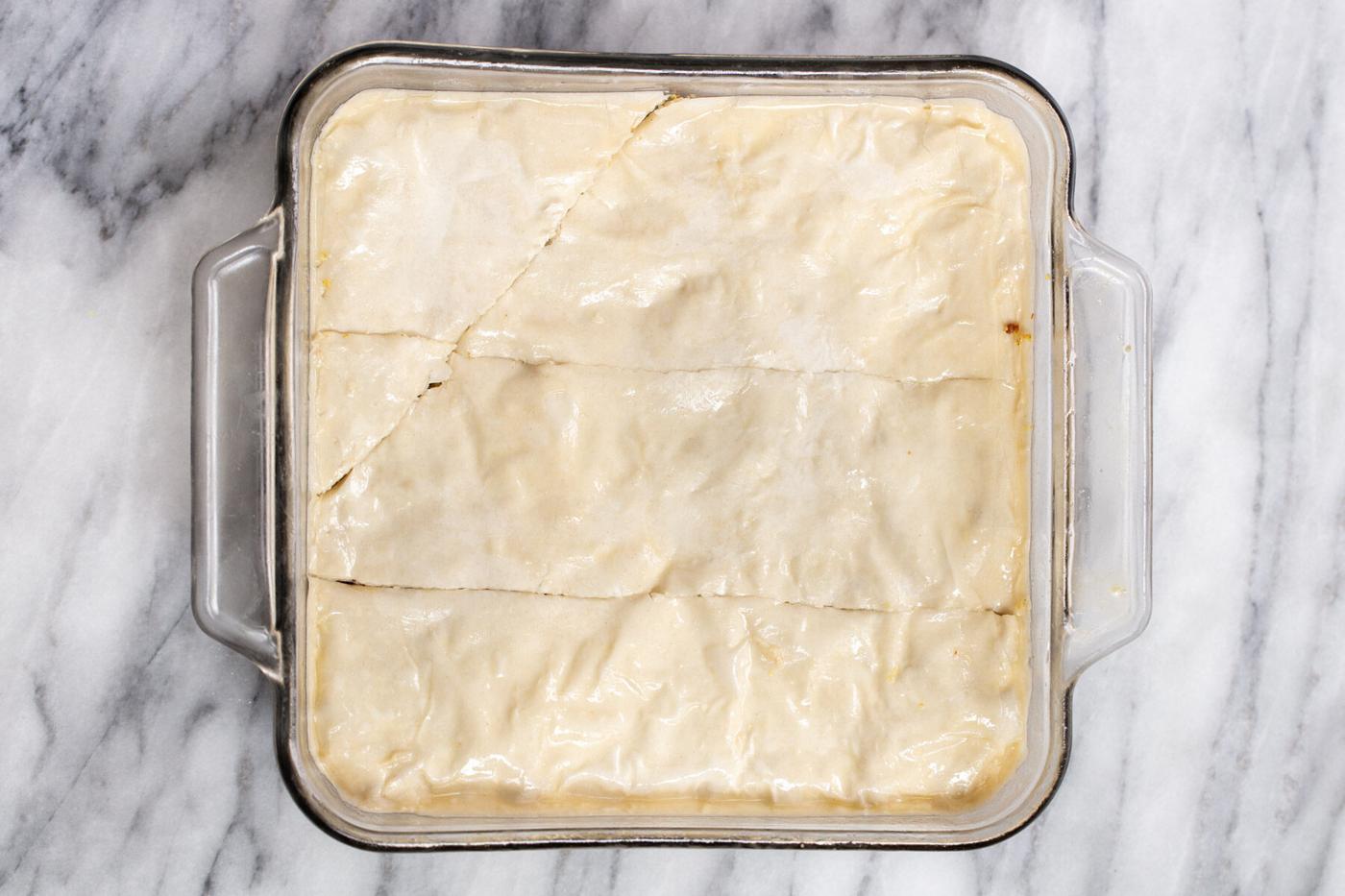 assembled vegan baklava being cut diagonally to make diamond shaped baklava pieces