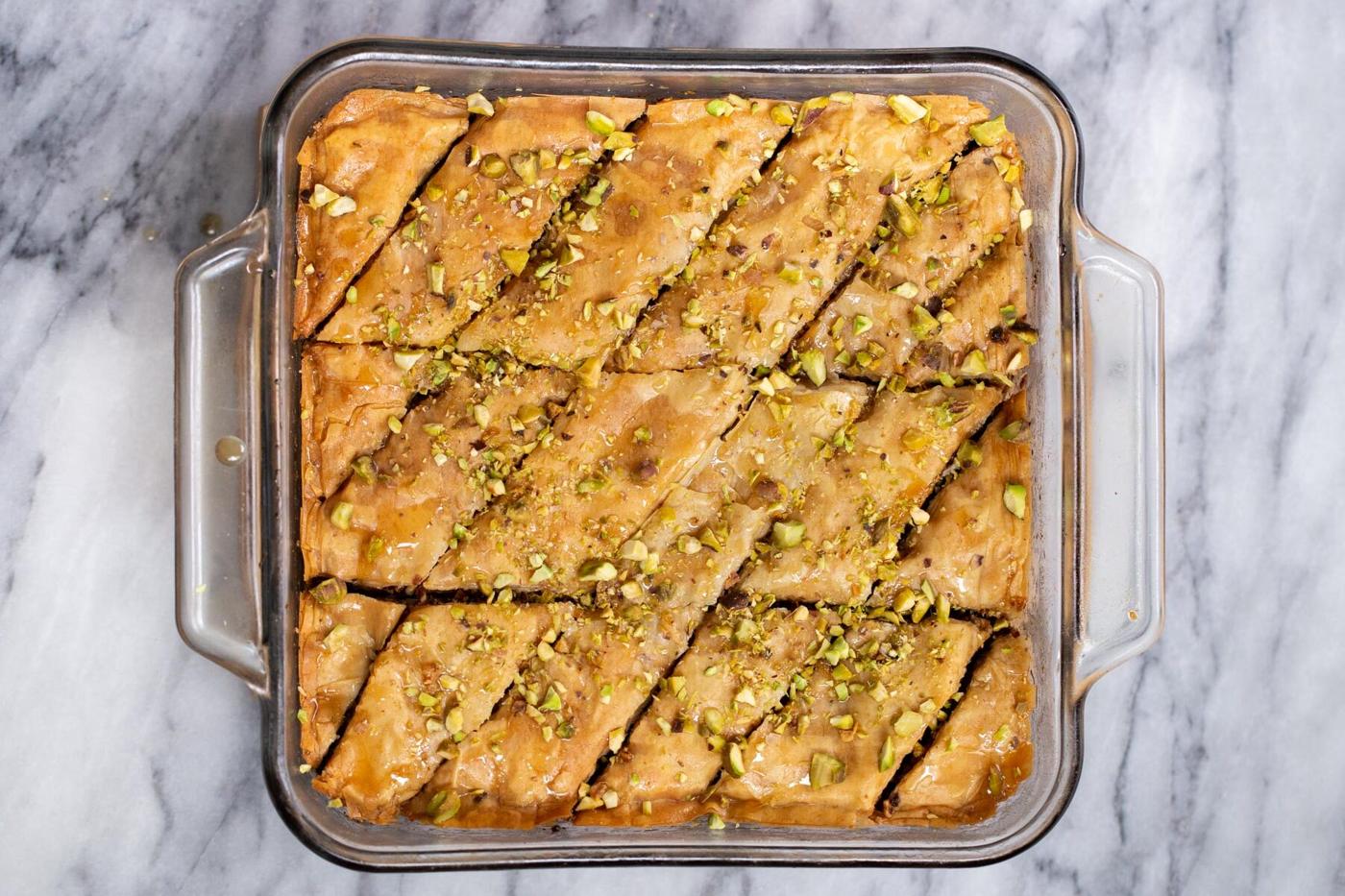 baked vegan baklava being sprinkled with pistachios
