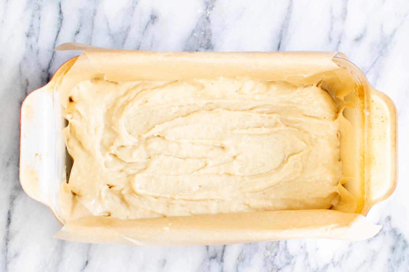 vegan cake batter being spread in a loaf pan