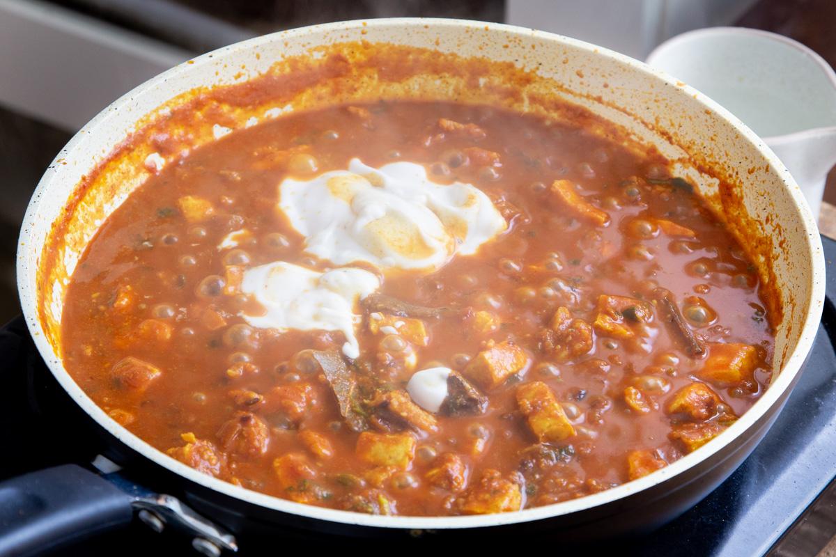 vegan balti chicken with tofu and vegan crumbles simmering in a sauteeing pan