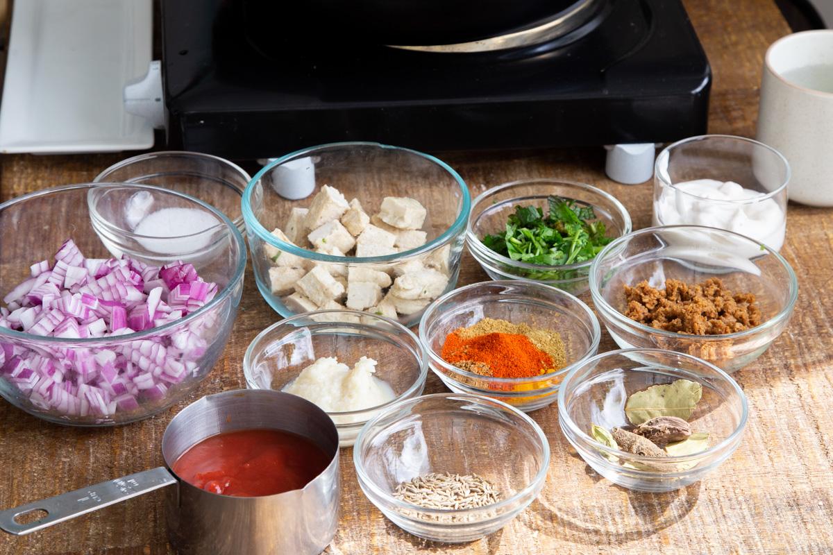 ingredients for making vegan balti chicken on a wooden chopping board